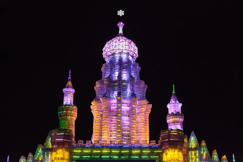 Illuminated ice buildings at Harbin Ice and Snow World glowing in blue and yellow at night