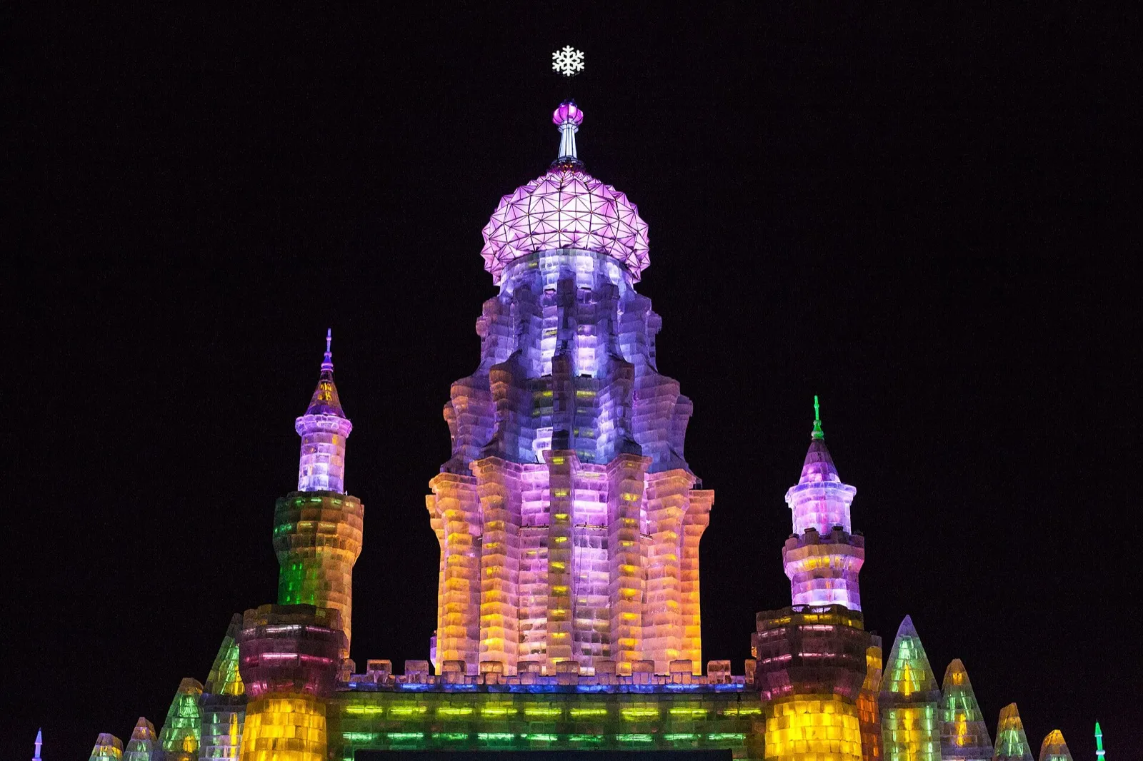 Illuminated ice buildings at Harbin Ice and Snow World glowing in blue and yellow at night
