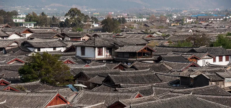 Lijiang Old Town rooftops with Jade Dragon Snow Mountain rising behind under a clear sky