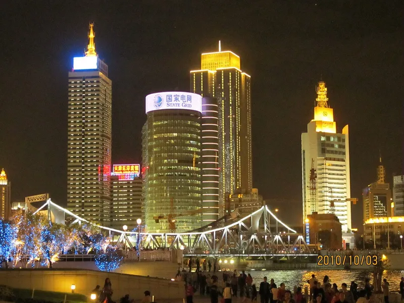 The illuminated skyline of Jinwan Plaza reflected in the Hai River at night, with the Tianjin Eye Ferris wheel visible in the distance