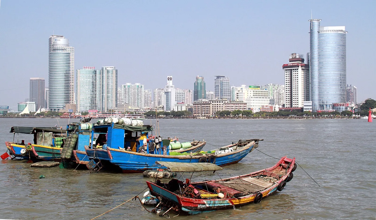 The Xiamen waterfront at dusk with Gulangyu Island's red-roofed villas across the harbor
