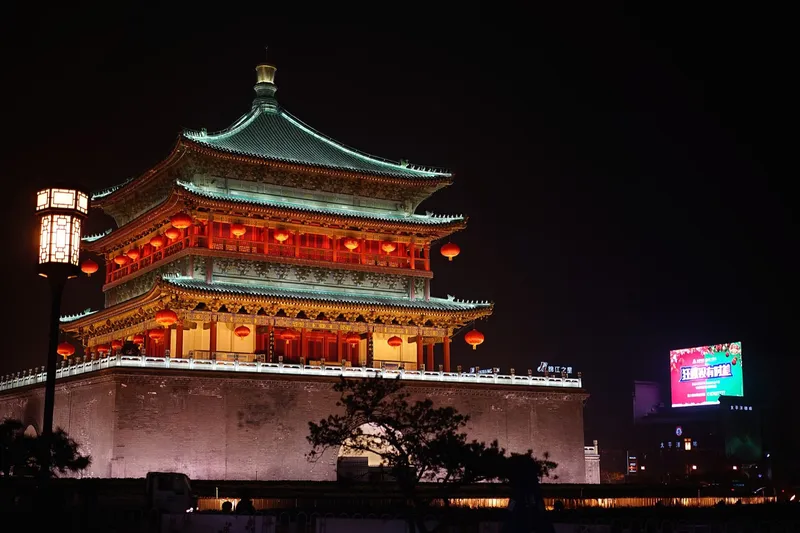 The illuminated Xi'an City Wall and Bell Tower at dusk with the Giant Wild Goose Pagoda in the distance