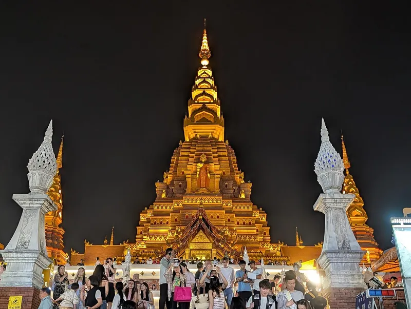The golden pagoda of Gaozhuang glowing above lantern-lit streets at night in Jinghong