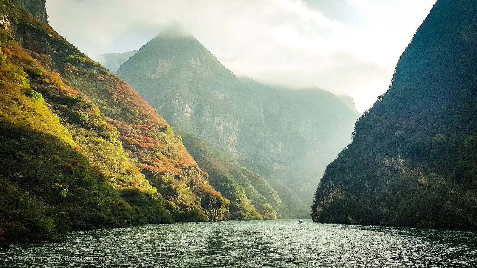 A multi-deck river cruise ship sailing between steep limestone cliffs in the Three Gorges